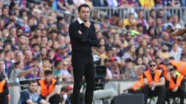 Xavi Hernández pensativo con una mano en la barbilla, vestido de negro.